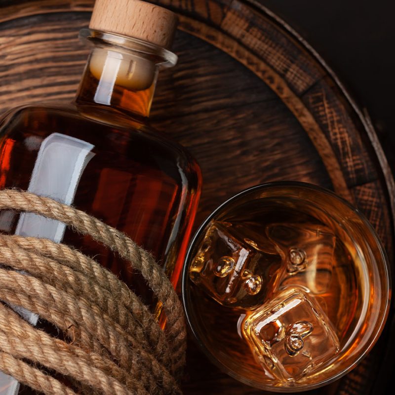 A bottle and glass of rum on a barrel